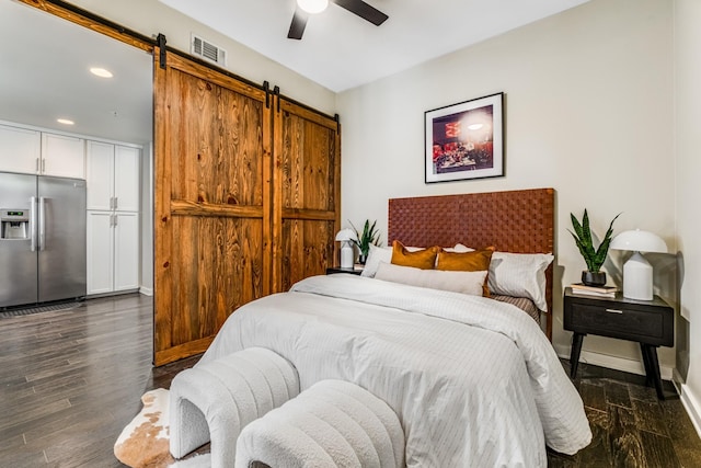 bedroom with stainless steel refrigerator with ice dispenser, ceiling fan, dark wood-type flooring, a barn door, and a closet