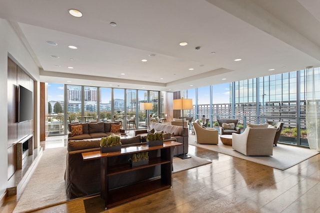 living room featuring expansive windows, light hardwood / wood-style flooring, and a tray ceiling