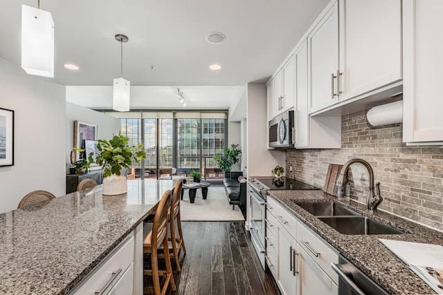 kitchen with white cabinets, stainless steel appliances, hanging light fixtures, and a breakfast bar