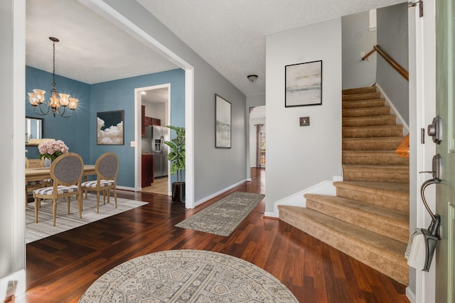 foyer with dark wood-type flooring, a textured ceiling, and a notable chandelier