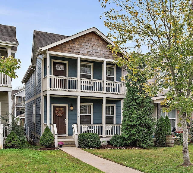 view of front of property featuring a balcony, a porch, and a front yard