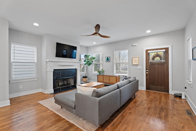 living room with a tile fireplace, hardwood / wood-style floors, and ceiling fan