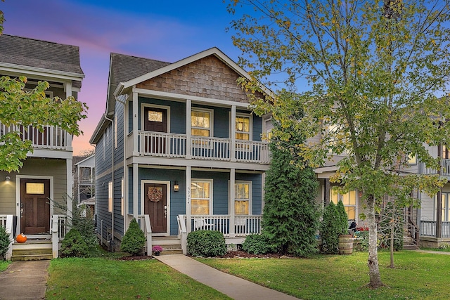 view of front of house with a porch, a yard, and a balcony