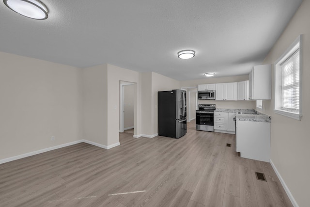 kitchen featuring a textured ceiling, white cabinets, light wood-type flooring, sink, and stainless steel appliances