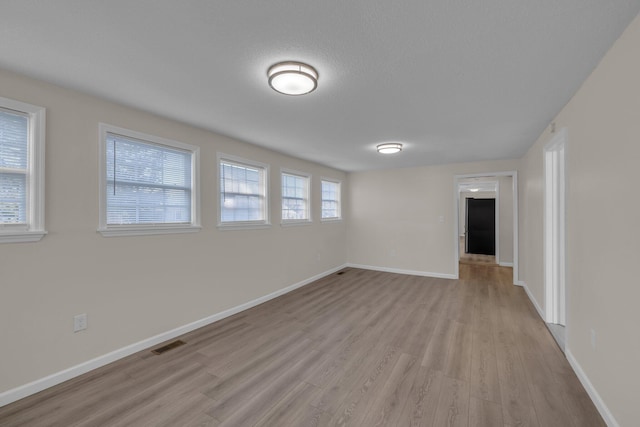 unfurnished room featuring light hardwood / wood-style flooring and a textured ceiling