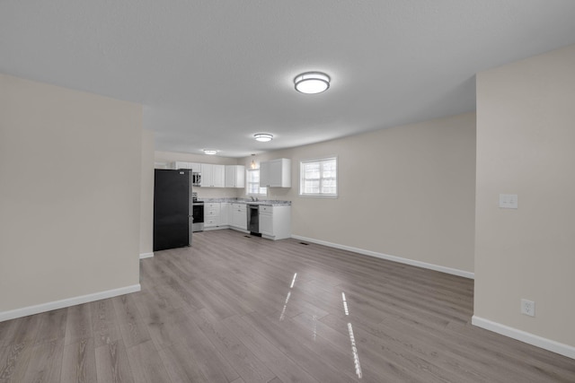 unfurnished living room featuring sink and light hardwood / wood-style flooring