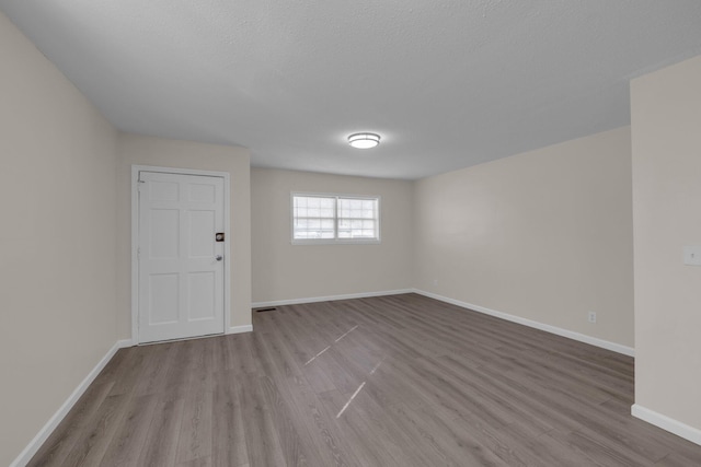 spare room with light wood-type flooring and a textured ceiling