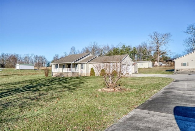 view of front of house featuring covered porch, a front lawn, and an outbuilding