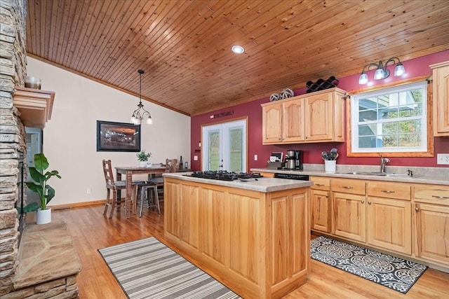 kitchen with pendant lighting, a center island, light brown cabinetry, light wood-type flooring, and gas stovetop