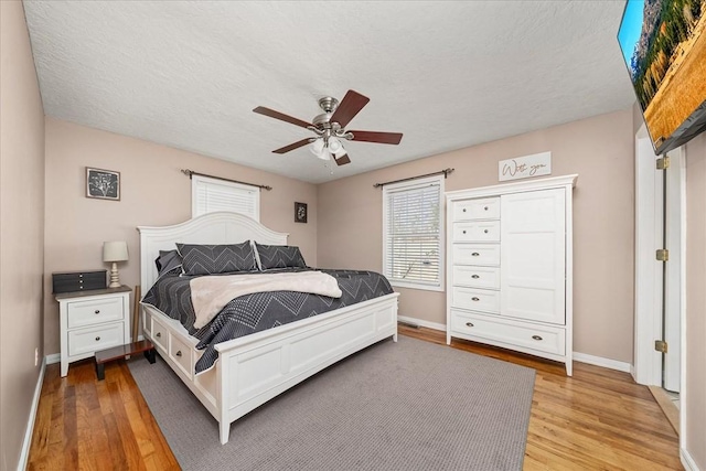 bedroom featuring light wood-type flooring, ceiling fan, and a textured ceiling