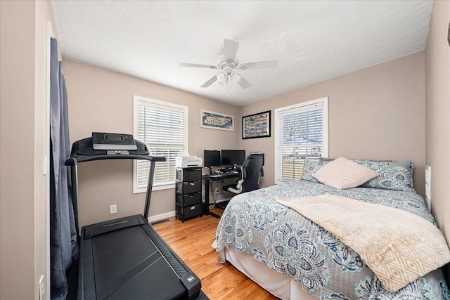 bedroom featuring multiple windows, hardwood / wood-style flooring, and ceiling fan