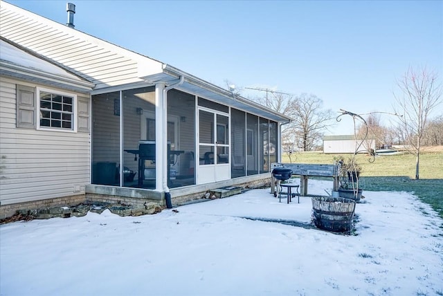 view of snow covered exterior with a sunroom