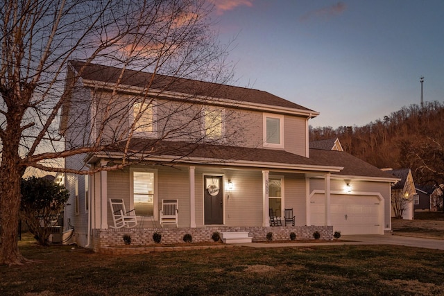 view of front of home with a garage, covered porch, and a yard