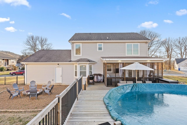 rear view of property featuring an outdoor fire pit and a pool side deck