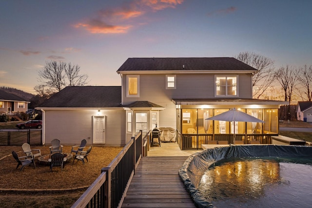 back house at dusk featuring an outdoor fire pit and a pool side deck