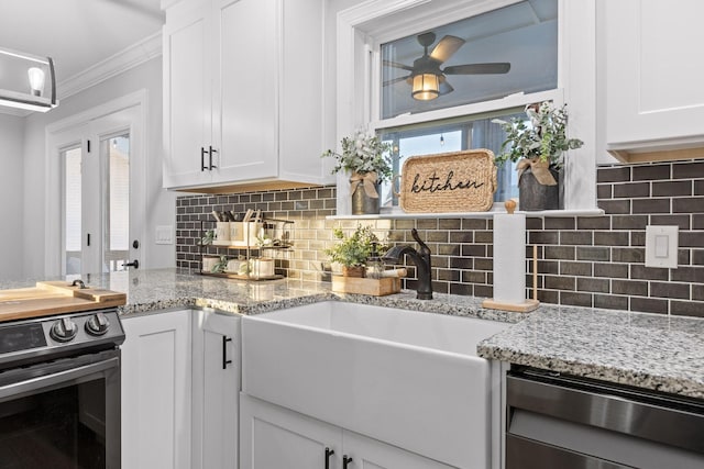 kitchen with white cabinets, ornamental molding, appliances with stainless steel finishes, and decorative backsplash