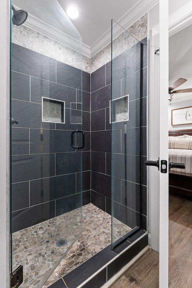 bathroom with wood-type flooring, a shower with door, ceiling fan, and ornamental molding