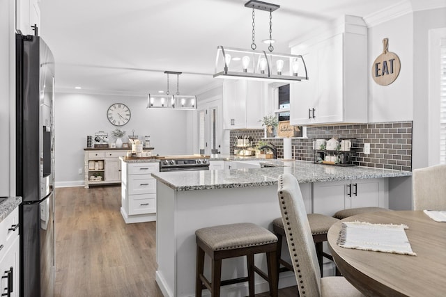 kitchen featuring tasteful backsplash, white cabinets, kitchen peninsula, stainless steel appliances, and light stone counters