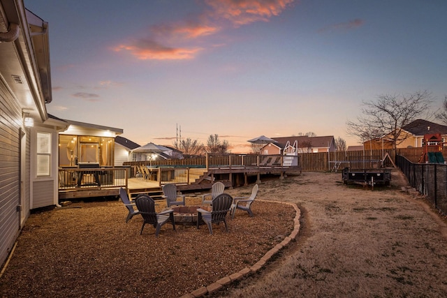 yard at dusk with a deck and a fire pit