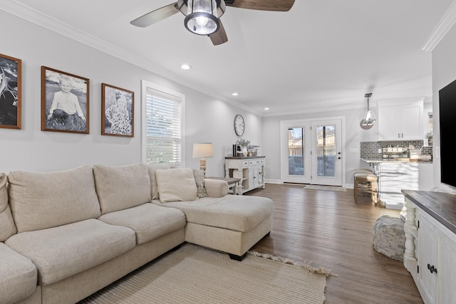 living room featuring wood-type flooring, ceiling fan, and ornamental molding