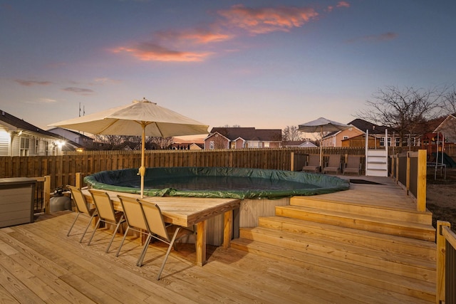 deck at dusk featuring a covered pool