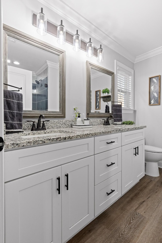 bathroom featuring crown molding, vanity, toilet, hardwood / wood-style flooring, and a tile shower