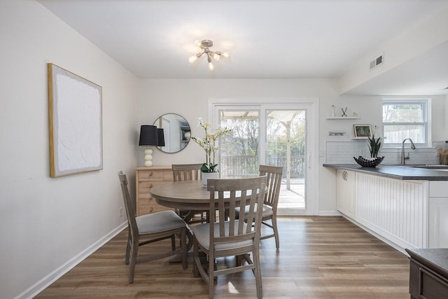 dining area featuring sink, hardwood / wood-style flooring, and an inviting chandelier