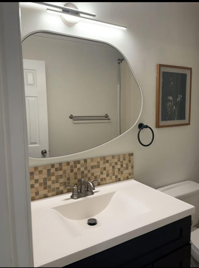 bathroom with vanity, toilet, and decorative backsplash