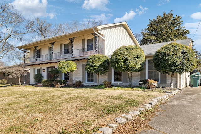 view of front of home with a balcony and a front lawn