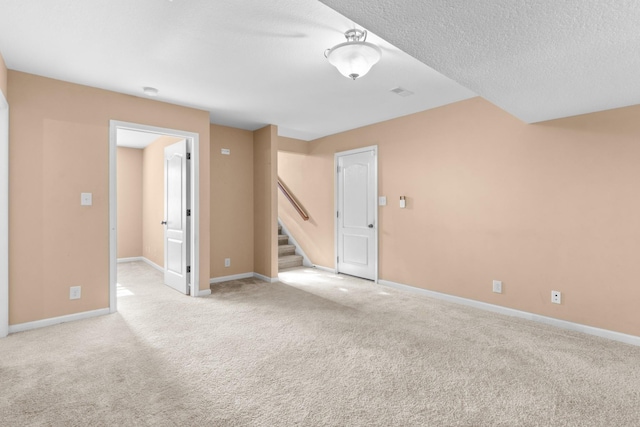 unfurnished room featuring a textured ceiling and light carpet