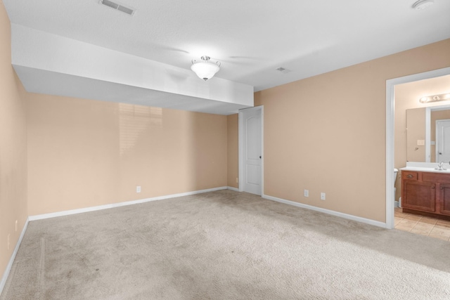 unfurnished bedroom with connected bathroom and light carpet