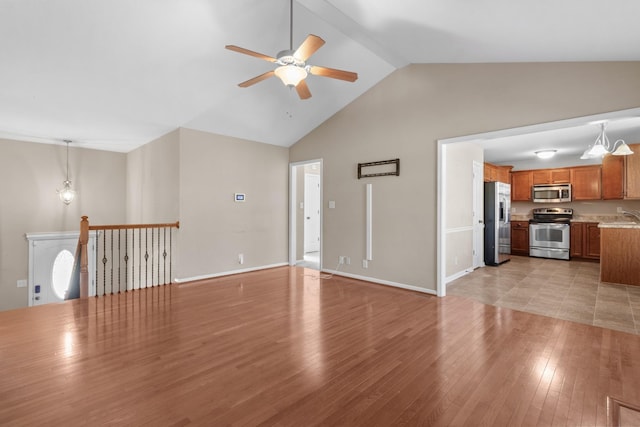 unfurnished living room featuring light hardwood / wood-style floors, sink, ceiling fan, and vaulted ceiling