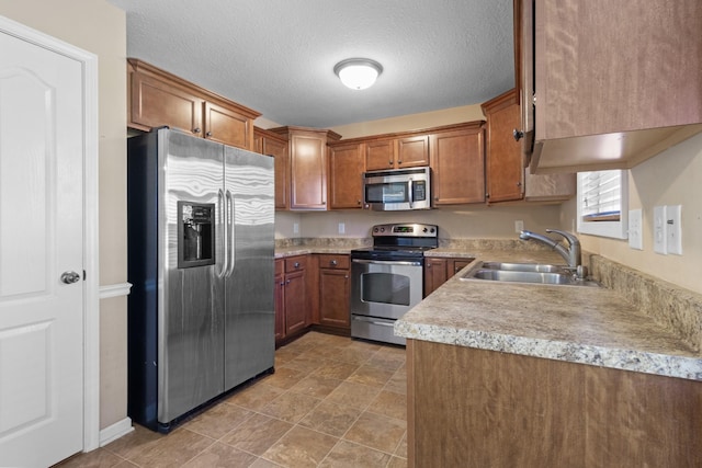 kitchen with sink, a textured ceiling, and stainless steel appliances