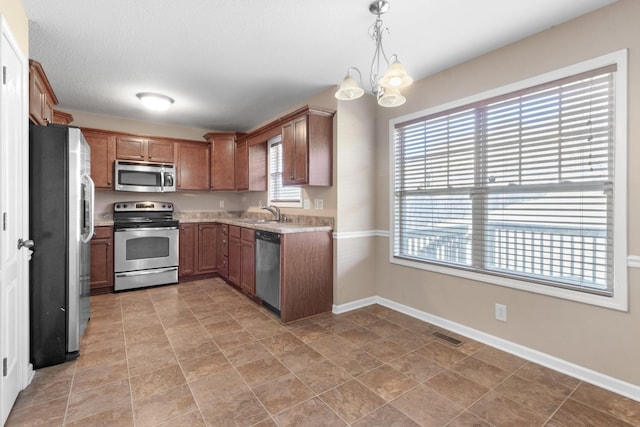 kitchen with decorative light fixtures, plenty of natural light, and appliances with stainless steel finishes