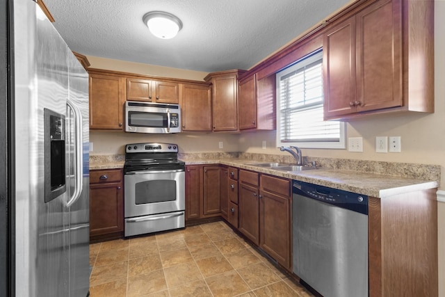 kitchen featuring sink, a textured ceiling, and stainless steel appliances