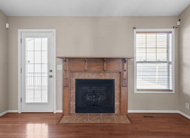 unfurnished living room with a tile fireplace and wood-type flooring