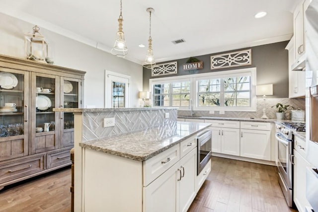 kitchen with white cabinetry, backsplash, appliances with stainless steel finishes, and a center island