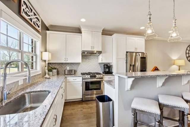 kitchen with sink, white cabinetry, appliances with stainless steel finishes, and a breakfast bar