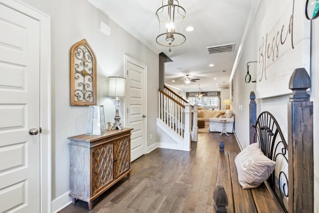 entryway with ceiling fan with notable chandelier, dark wood-type flooring, and ornamental molding