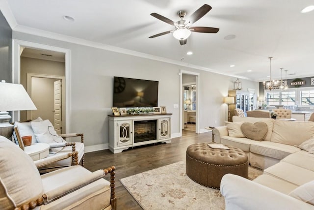 living room with ceiling fan with notable chandelier, crown molding, dark wood-type flooring, and a fireplace