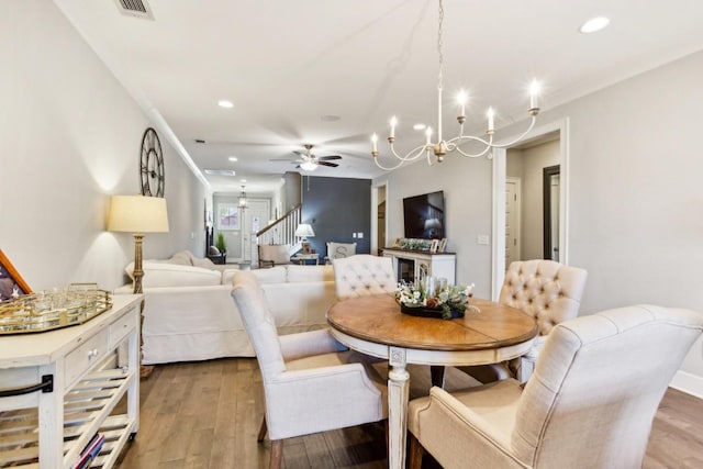 dining area with ceiling fan with notable chandelier and hardwood / wood-style floors