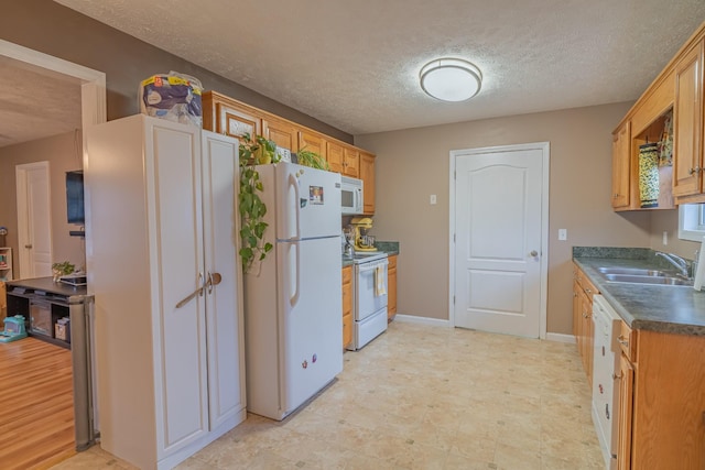 kitchen with sink, white appliances, and a textured ceiling