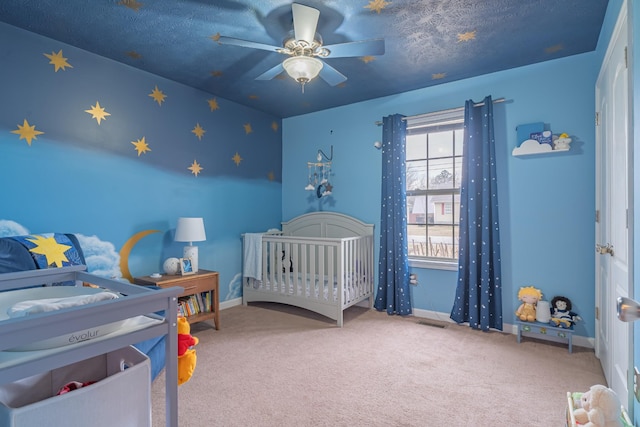 carpeted bedroom with ceiling fan and a nursery area