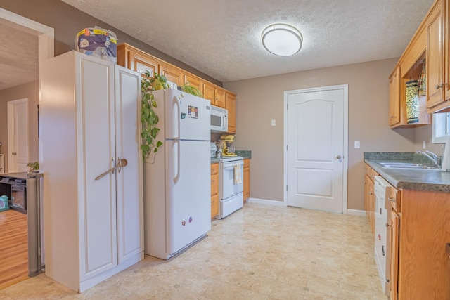 kitchen with sink, white appliances, and a textured ceiling