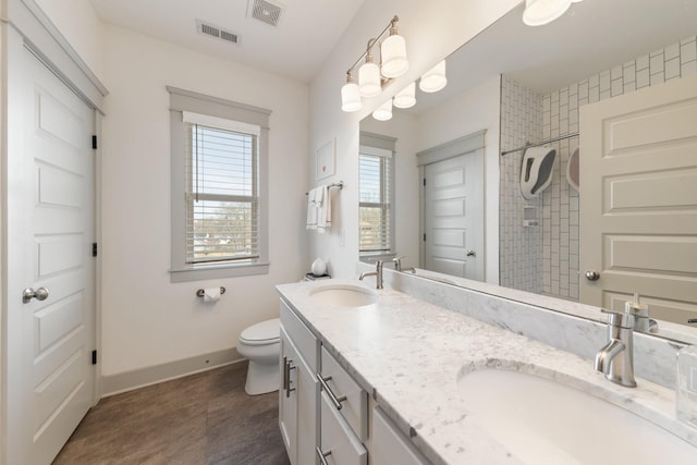 bathroom with toilet, vanity, and a tile shower