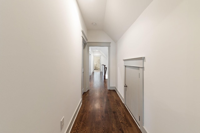 corridor with dark hardwood / wood-style floors and lofted ceiling