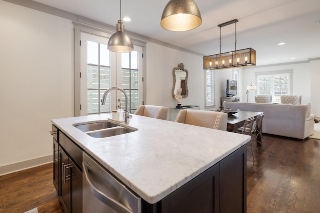 kitchen featuring stainless steel dishwasher, dark hardwood / wood-style flooring, sink, decorative light fixtures, and a center island with sink