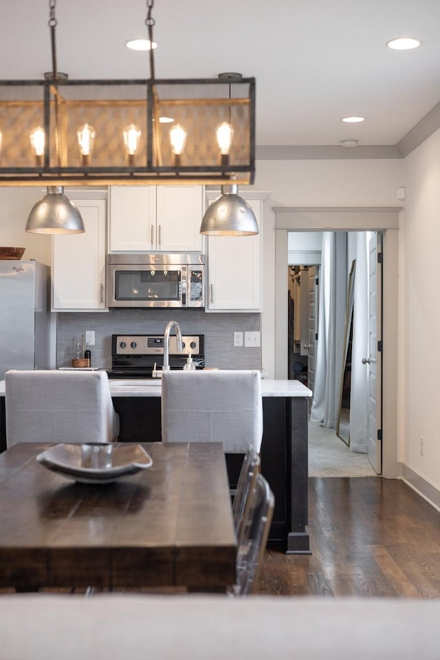 kitchen featuring white cabinets, pendant lighting, appliances with stainless steel finishes, and tasteful backsplash