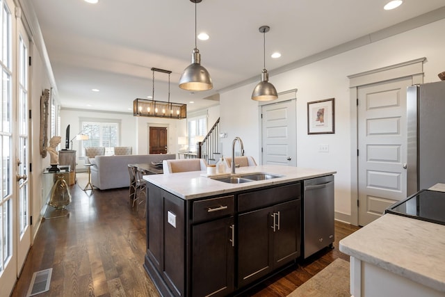 kitchen with pendant lighting, appliances with stainless steel finishes, sink, dark hardwood / wood-style floors, and a center island with sink