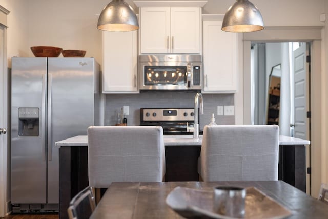 kitchen featuring backsplash, white cabinetry, pendant lighting, and stainless steel appliances